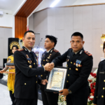 Kapolres Halmahera Selatan, AKBP Hendra Gunawan, menyerahkan penghargaan kepada Kapolsek Gane Barat, Ipda Ruslan Anwar, pada peringatan Hari Bhayangkara ke-80 Tahun 2026.